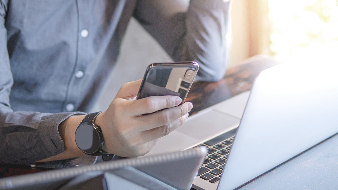 mano con telefono y computadora